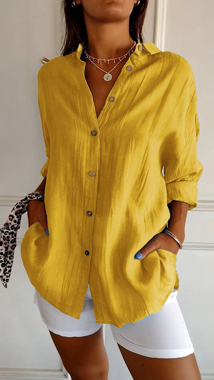 Person wearing a yellow button-up shirt and white shorts against a neutral background