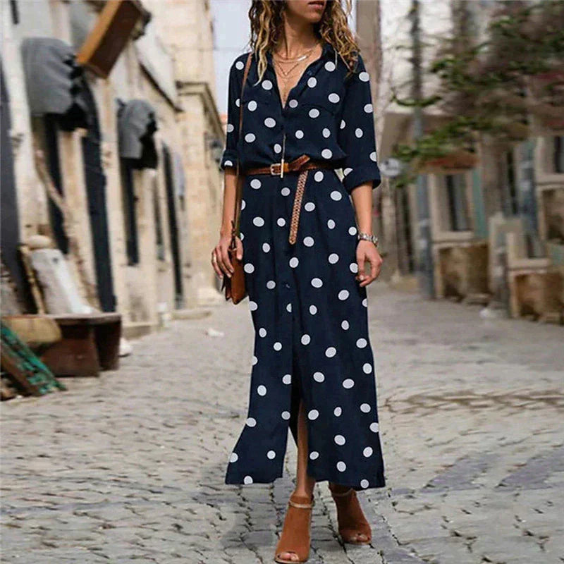 Woman wearing a navy blue dress with white polka dots on a cobblestone street.