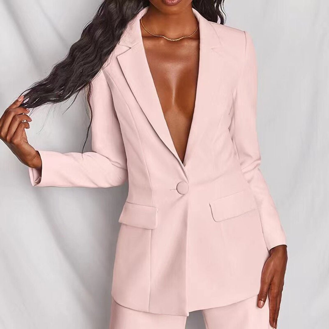 Person wearing a light pink suit against a plain background