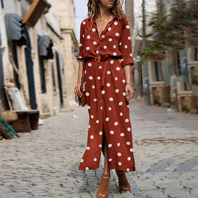 Woman wearing a brown polka dot dress on a cobblestone street.