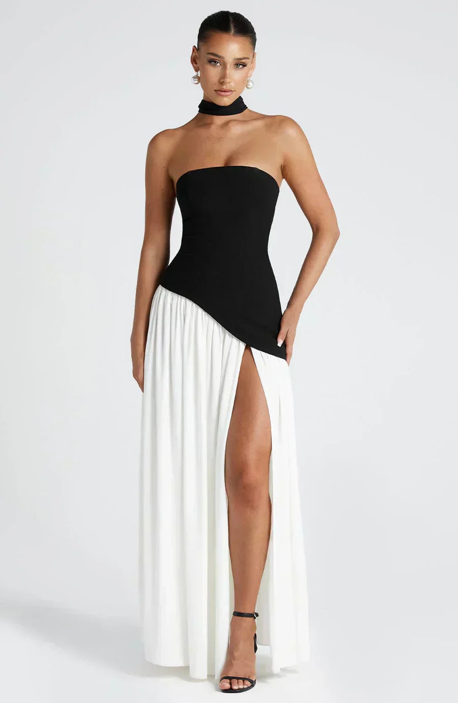 Woman wearing a black and white dress with a high slit on a white background