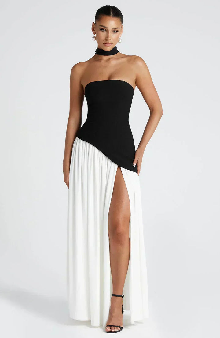 Woman wearing a black and white dress with a high slit on a white background