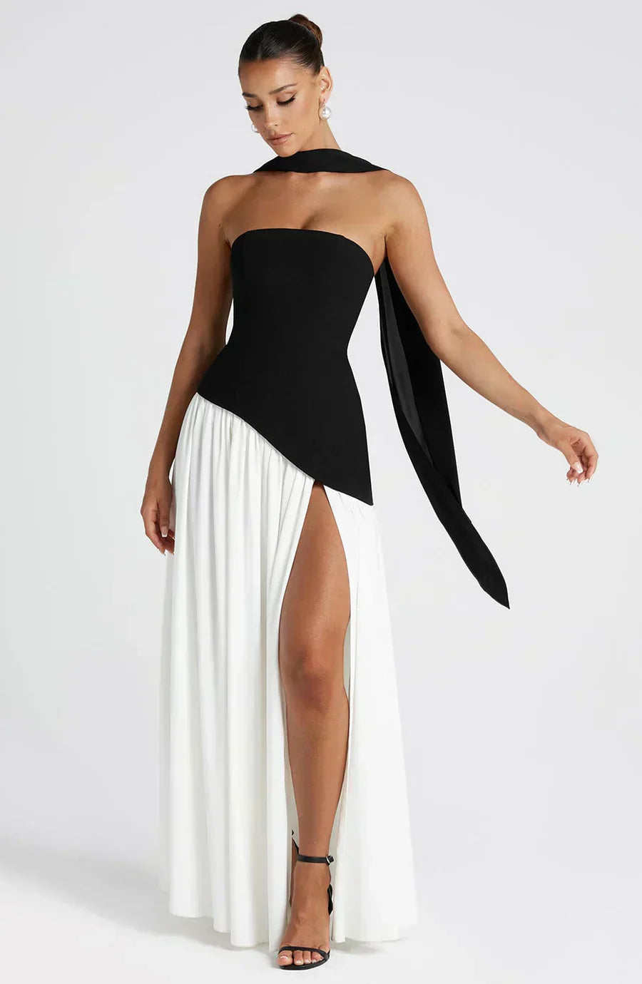 Woman wearing a black and white dress with a long train on a white background
