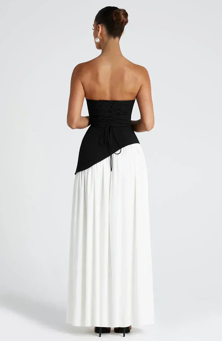 Woman wearing a black and white strapless dress on a white background
