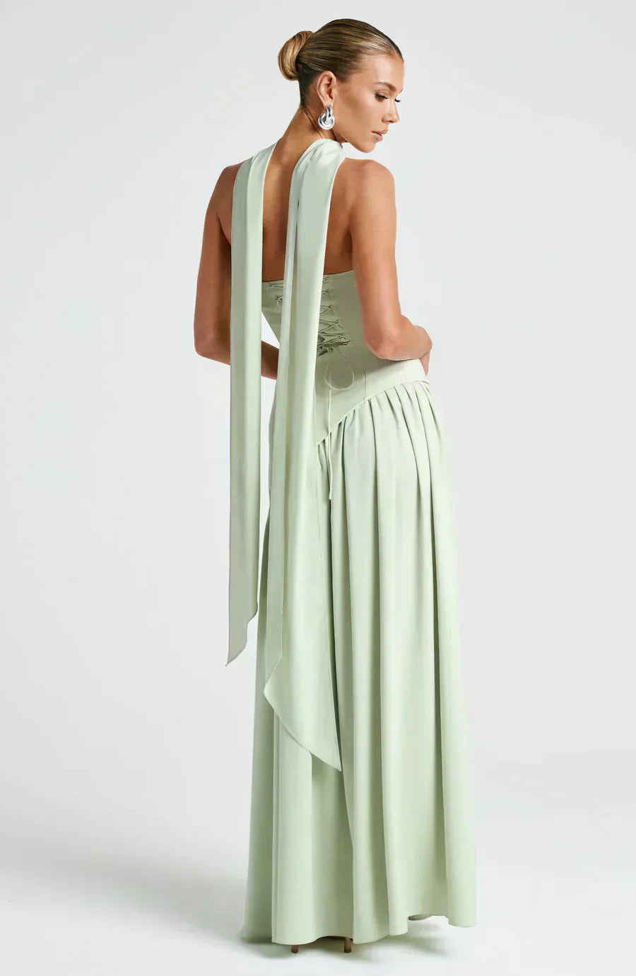 Woman wearing a light green evening gown with a flowing train on a white background