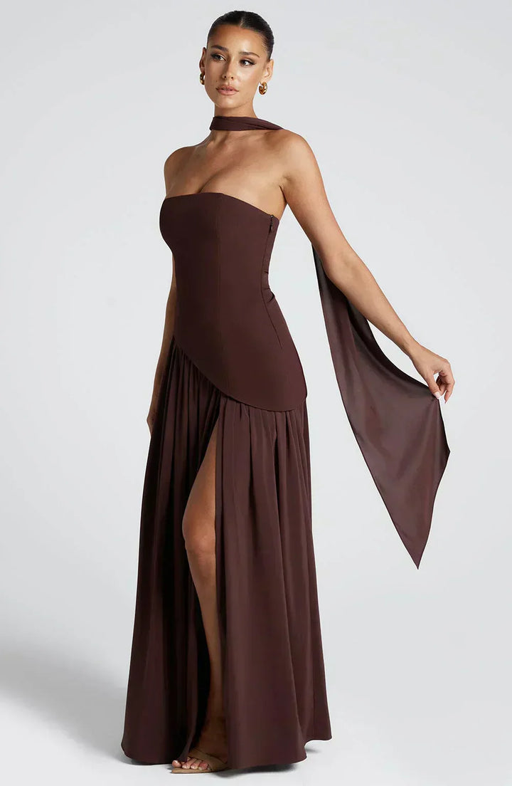 Woman wearing a brown strapless gown with a slit on a white background