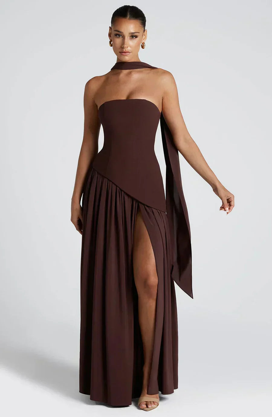Woman wearing a brown strapless gown with a slit on a white background