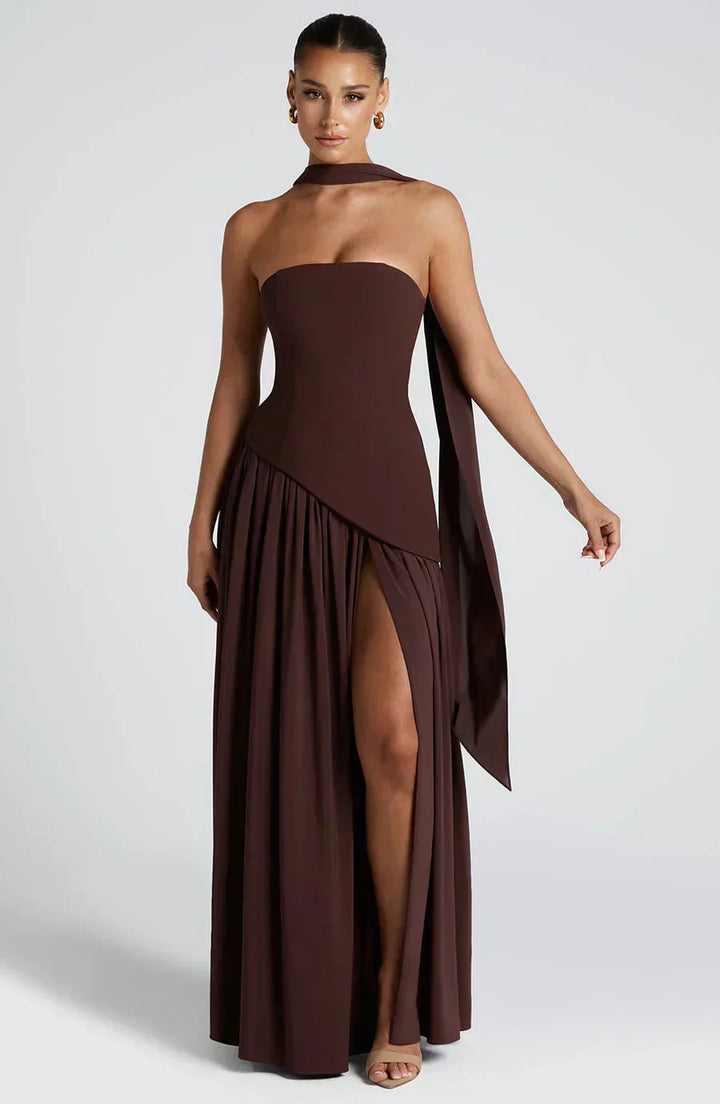 Woman wearing a brown strapless gown with a slit on a white background