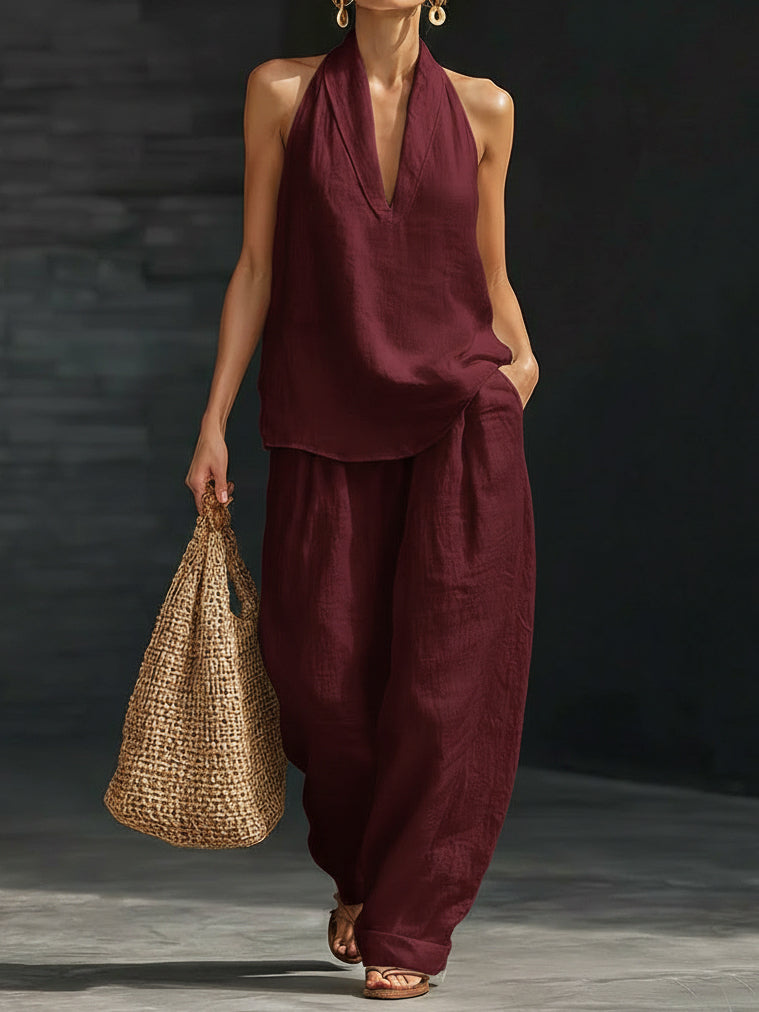 Woman wearing a burgundy outfit holding a woven bag against a dark background