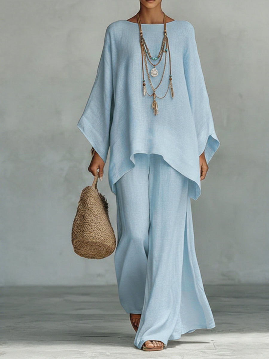 Woman wearing a light blue dress holding a woven bag against a gray background