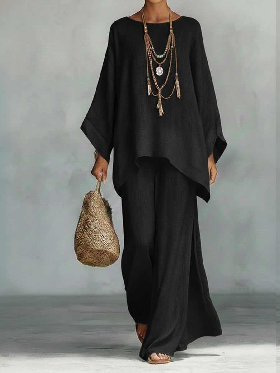 Person wearing a black outfit with a textured bag against a neutral background