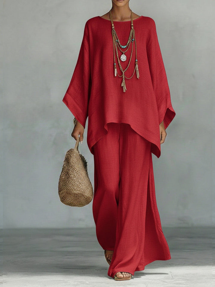Person wearing a red outfit with a textured necklace against a gray background