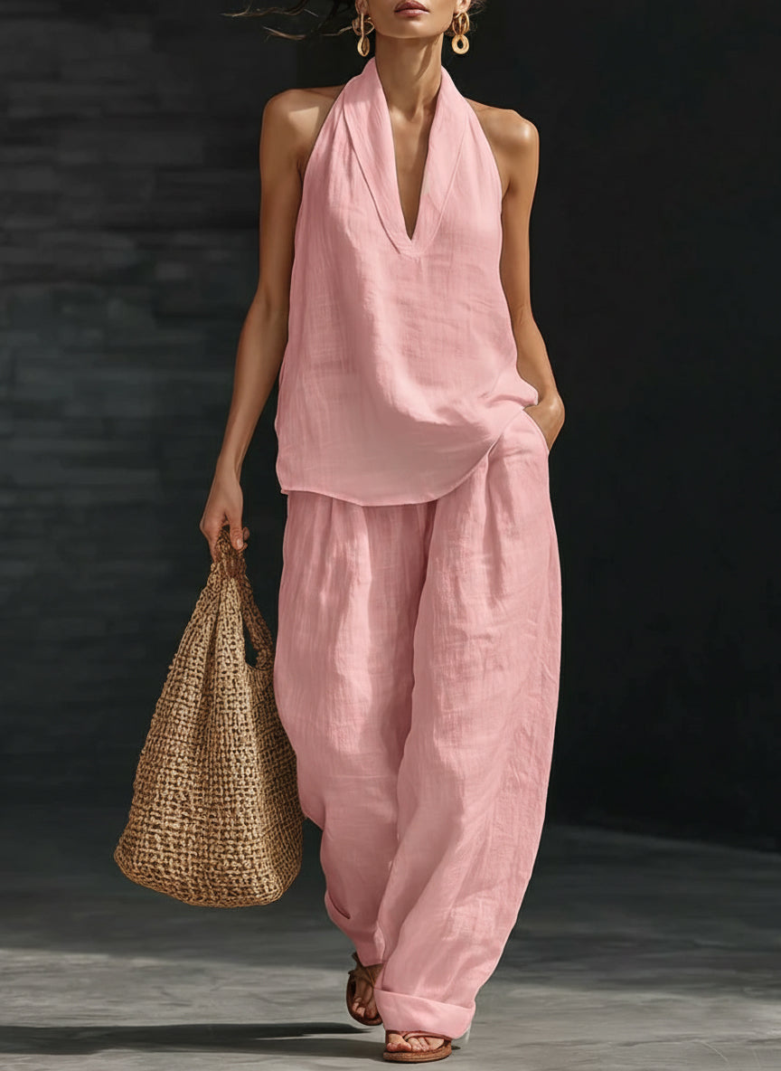 Woman in a pink outfit holding a straw bag against a dark background