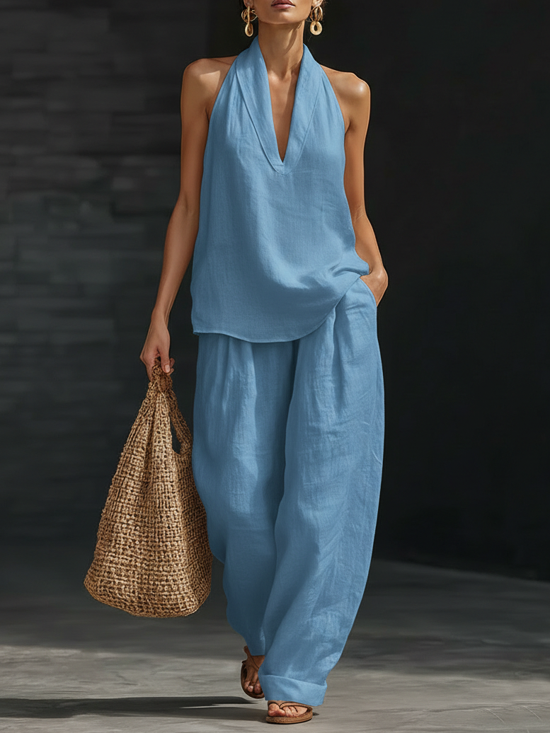 Woman in a blue outfit holding a woven bag against a dark background