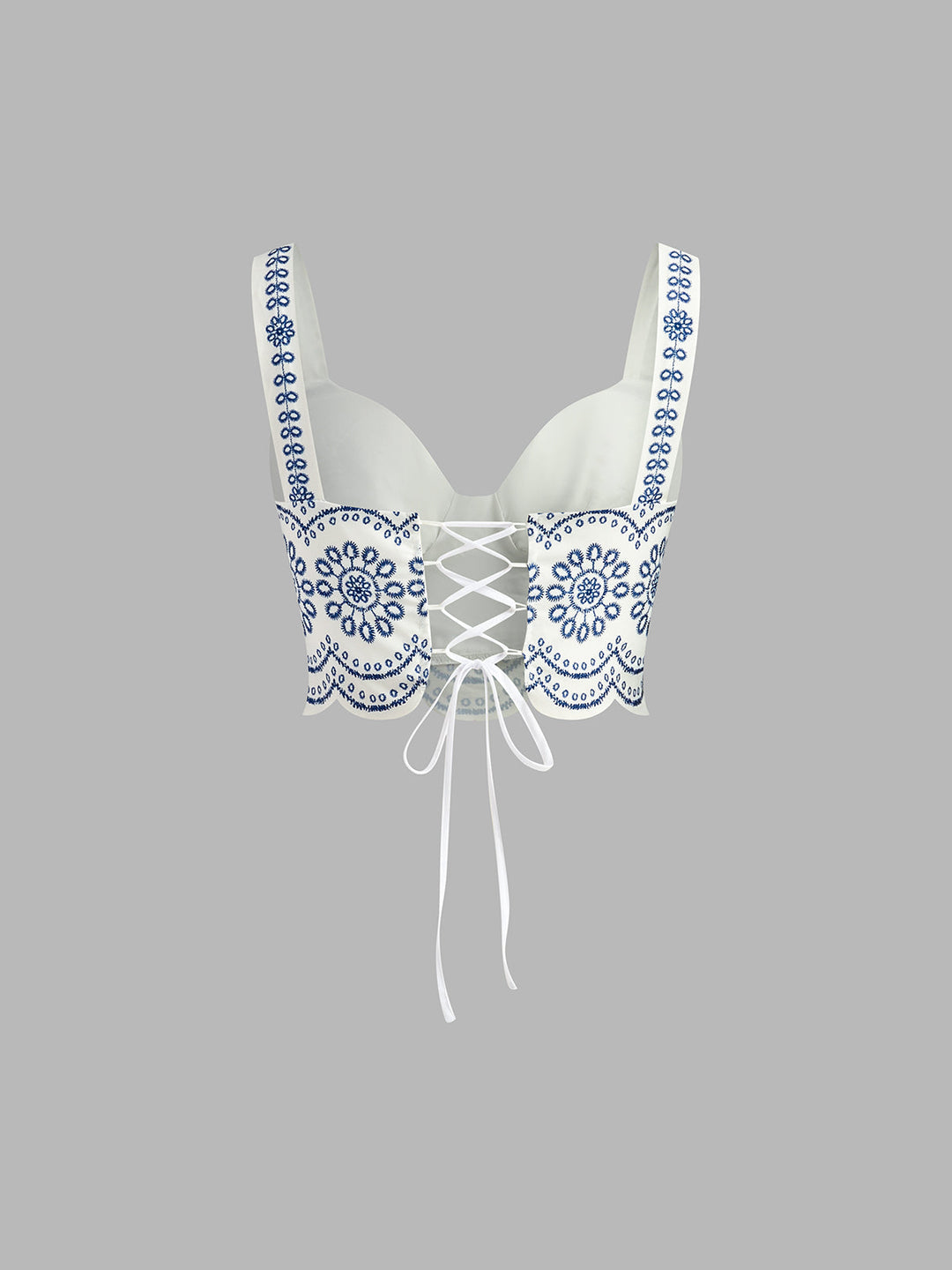 White lace-up bra with blue floral patterns on a gray background