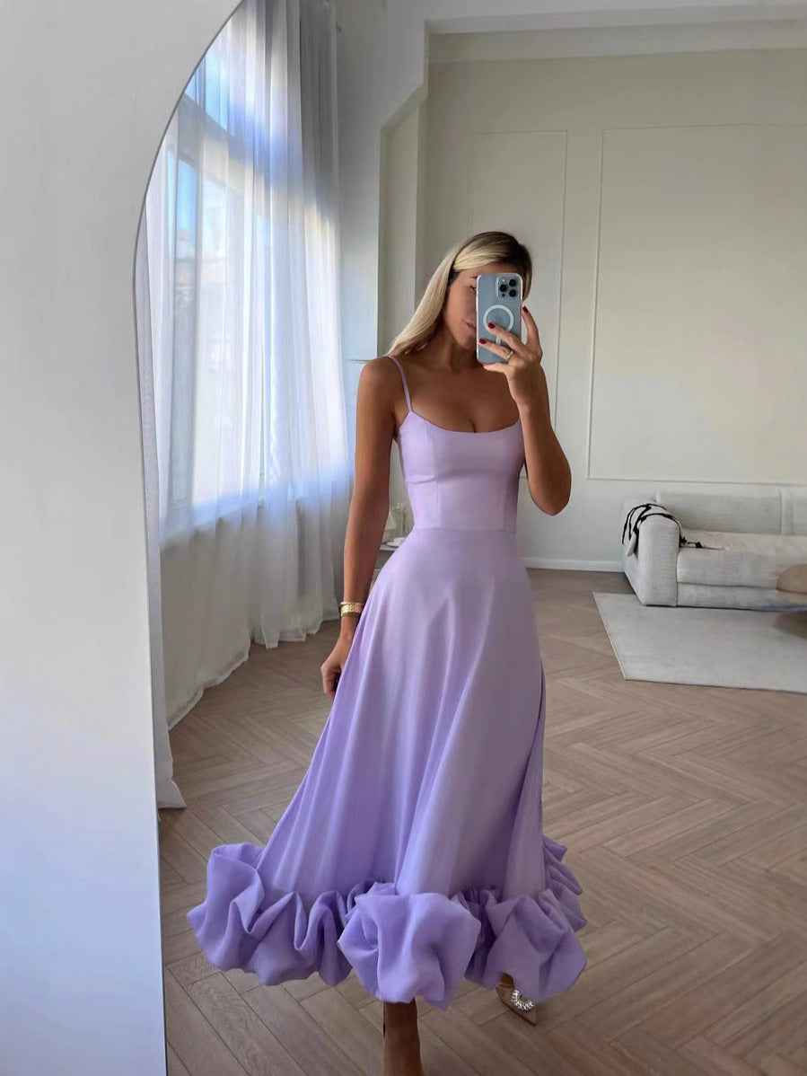 Woman in a lavender dress taking a mirror selfie in a room with white walls and a sofa.