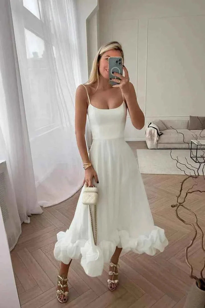 Woman in a white dress taking a mirror selfie in a bright room.