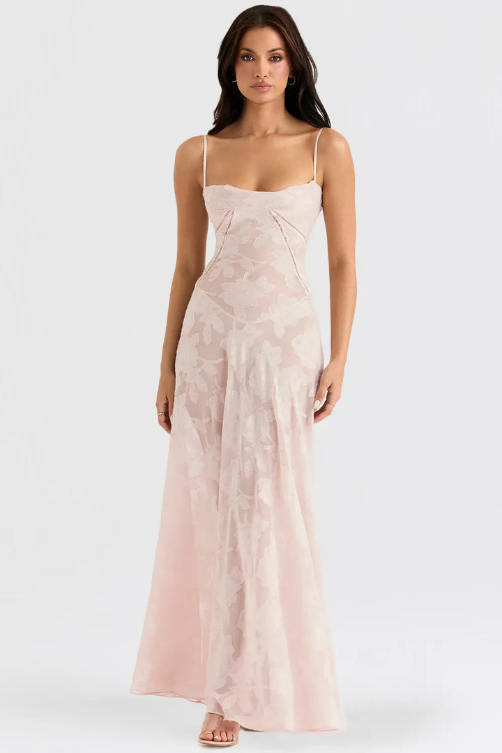 Woman wearing a long, light pink dress with thin straps on a white background