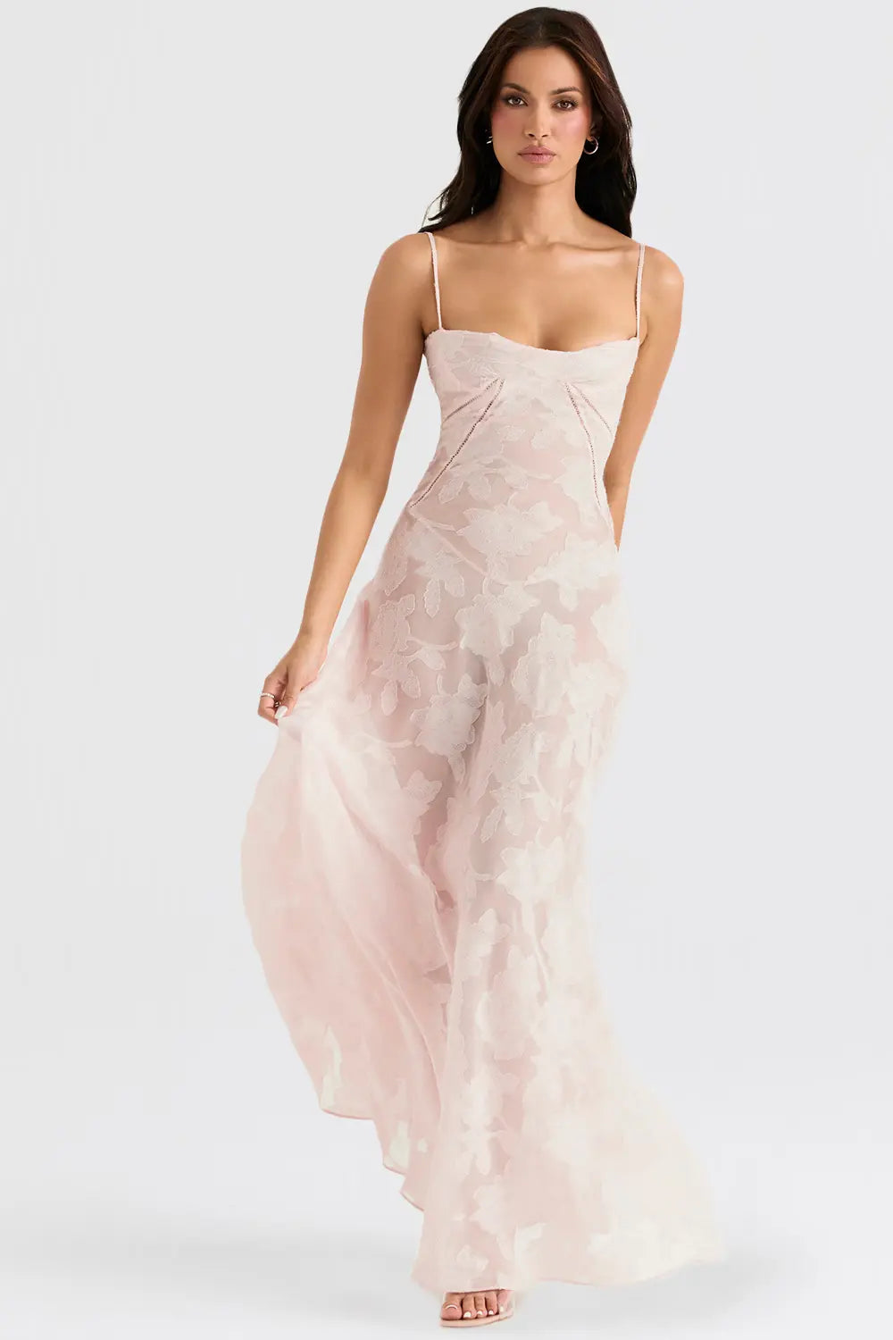 Woman wearing a light pink floral dress on a white background