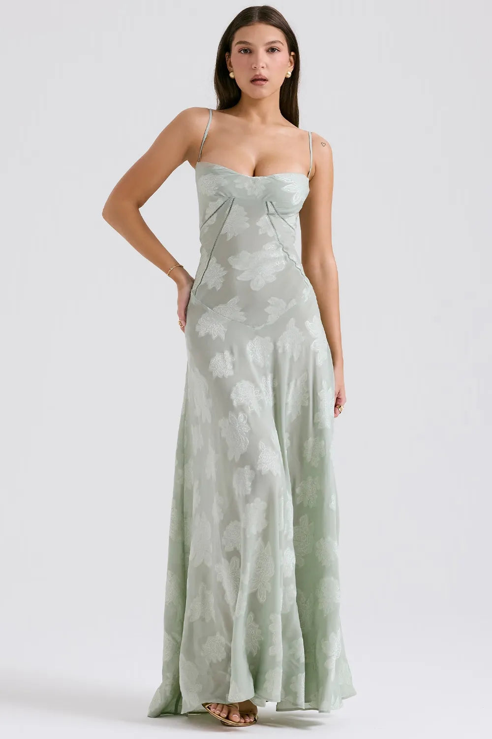 Woman wearing a strapless green dress with floral pattern on a white background