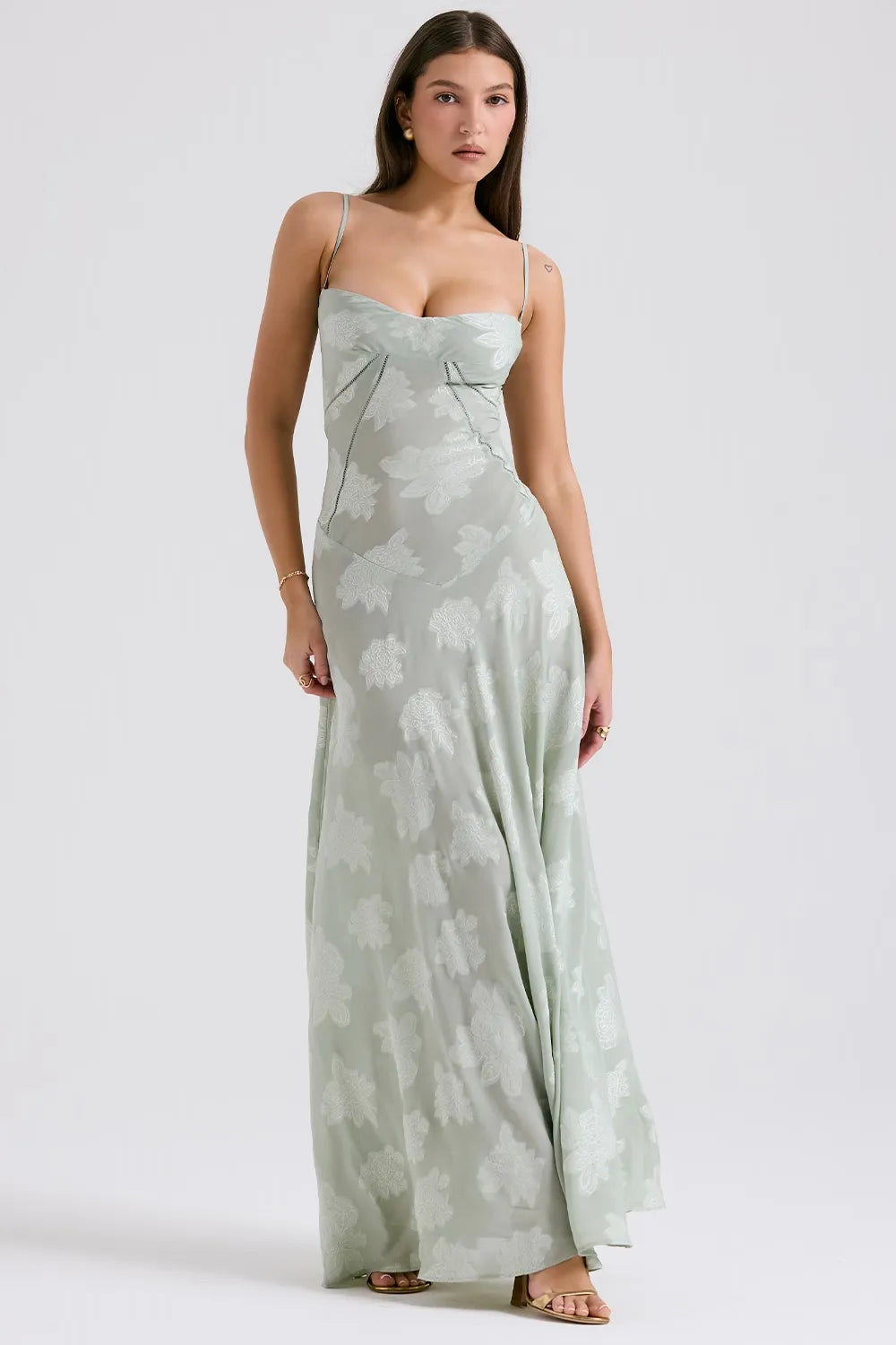 Woman wearing a light green floral dress on a white background