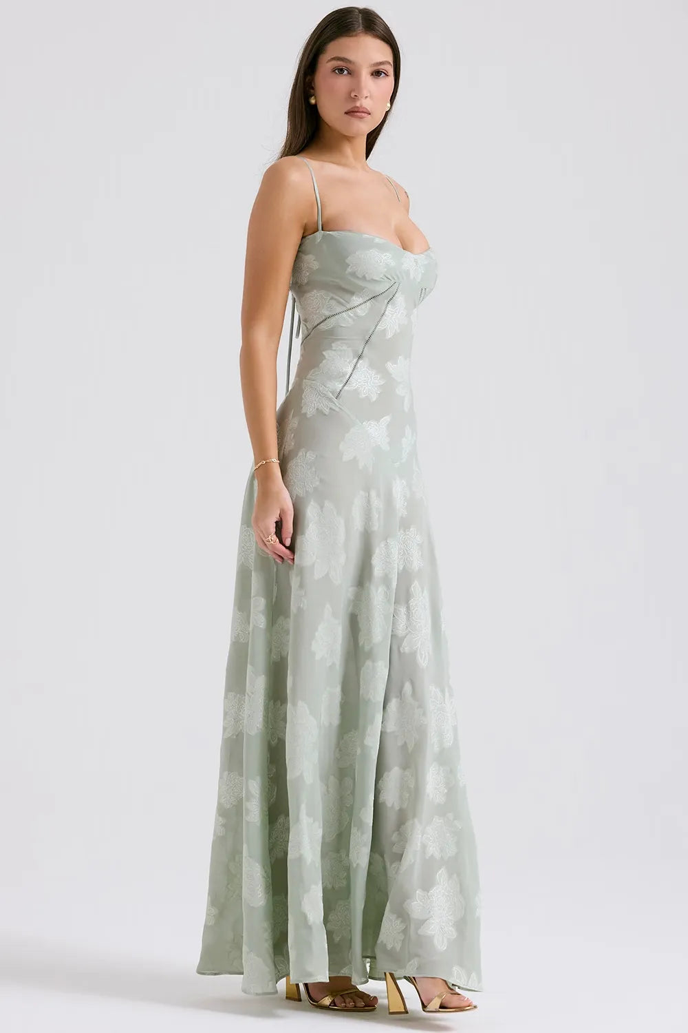 Woman wearing a strapless, long, light green dress with a subtle pattern on a white background