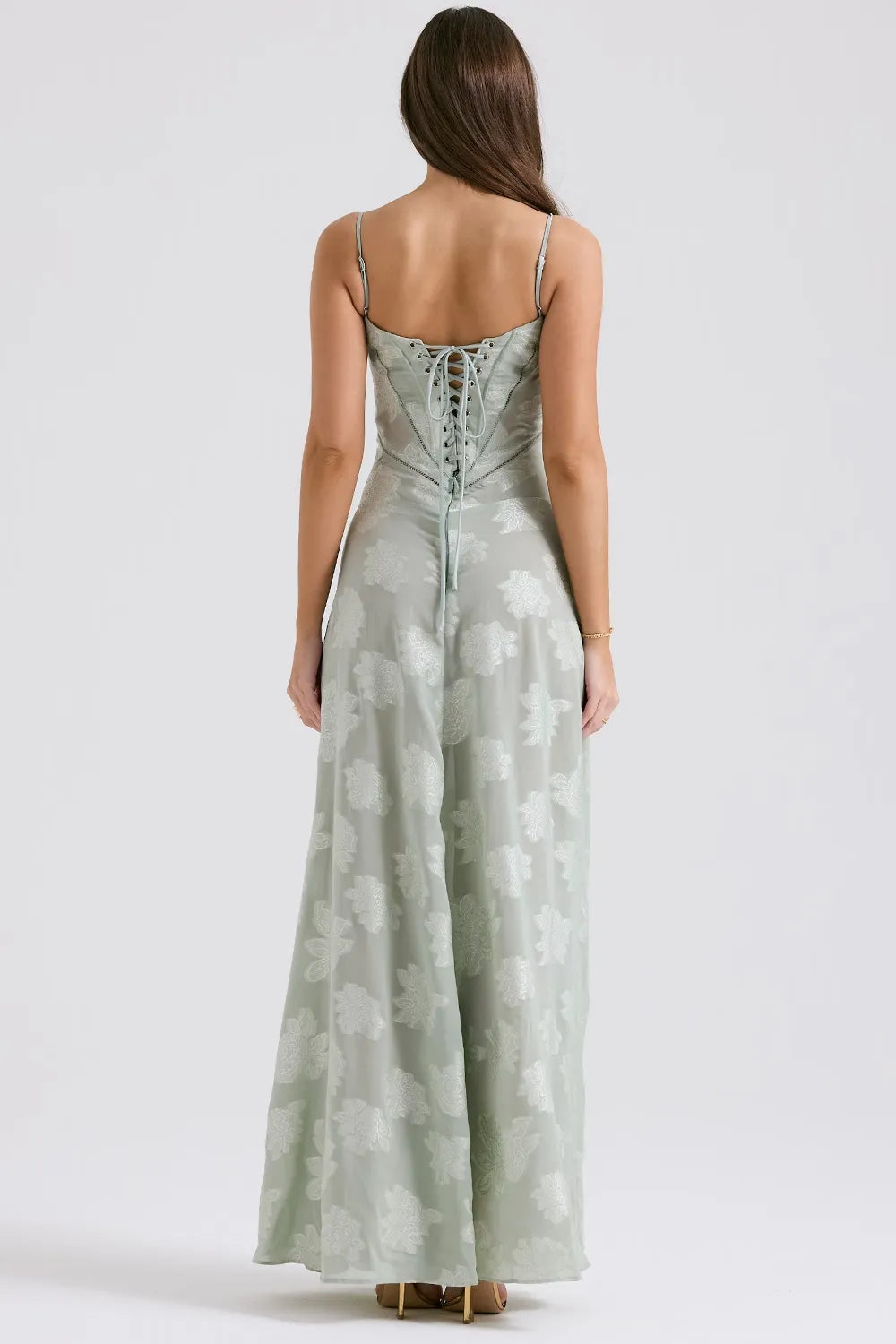 Woman wearing a light green floral dress on a white background