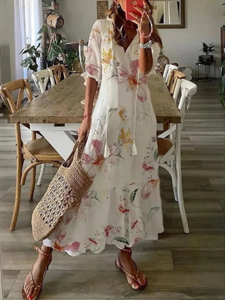 Woman in a floral dress holding a straw bag in a dining room.