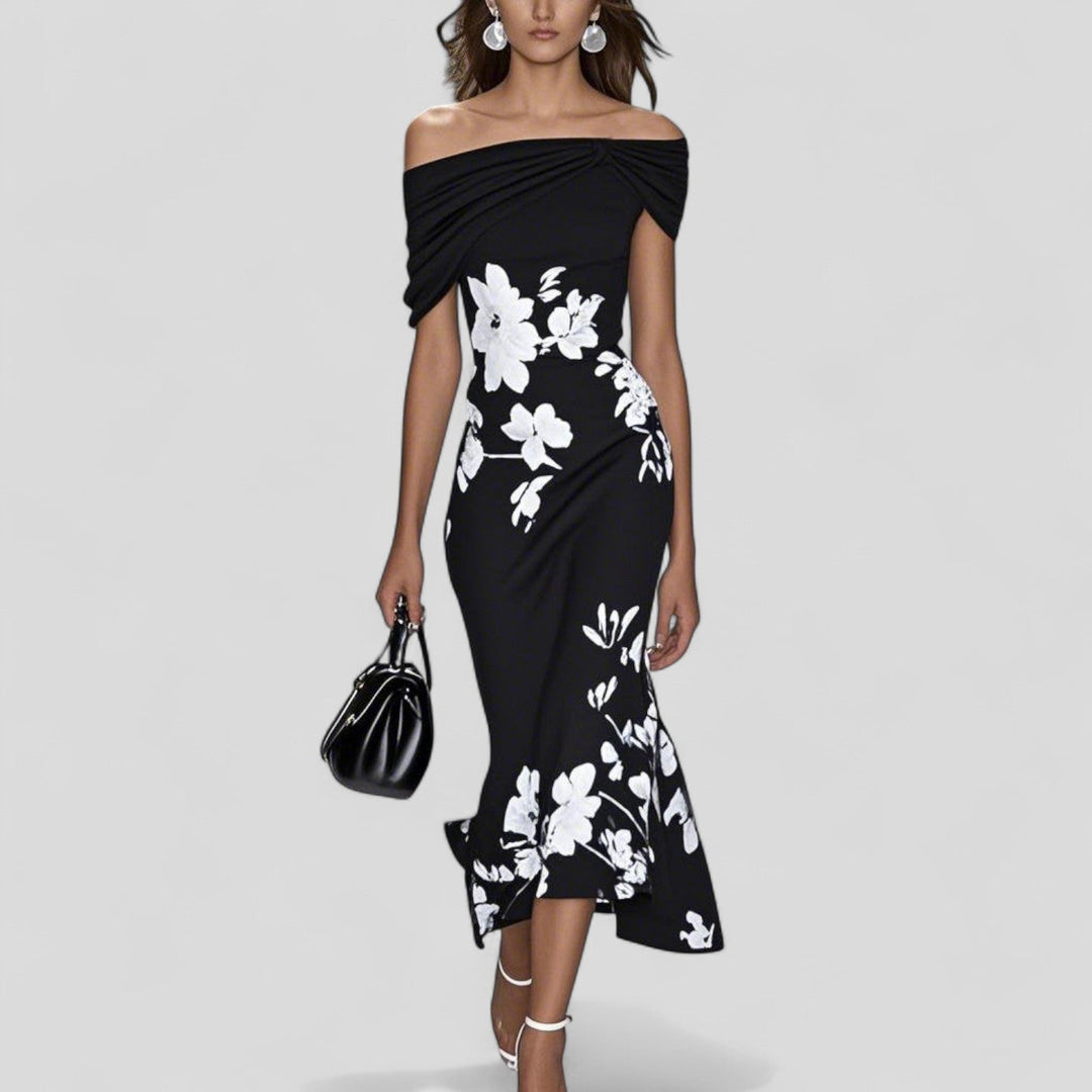 Woman wearing a black off-shoulder dress with white floral patterns on a gray background