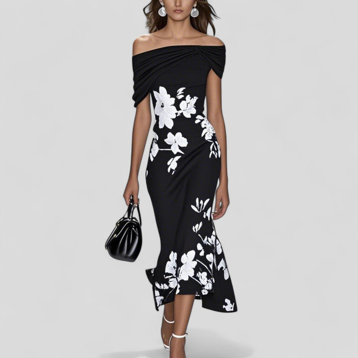 Woman wearing a black off-shoulder dress with white floral patterns on a gray background