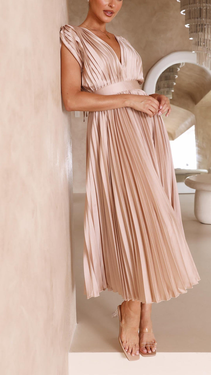 Woman wearing a pleated beige dress in an indoor setting