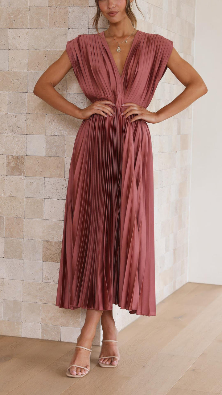 Woman wearing a pleated dress against a neutral background