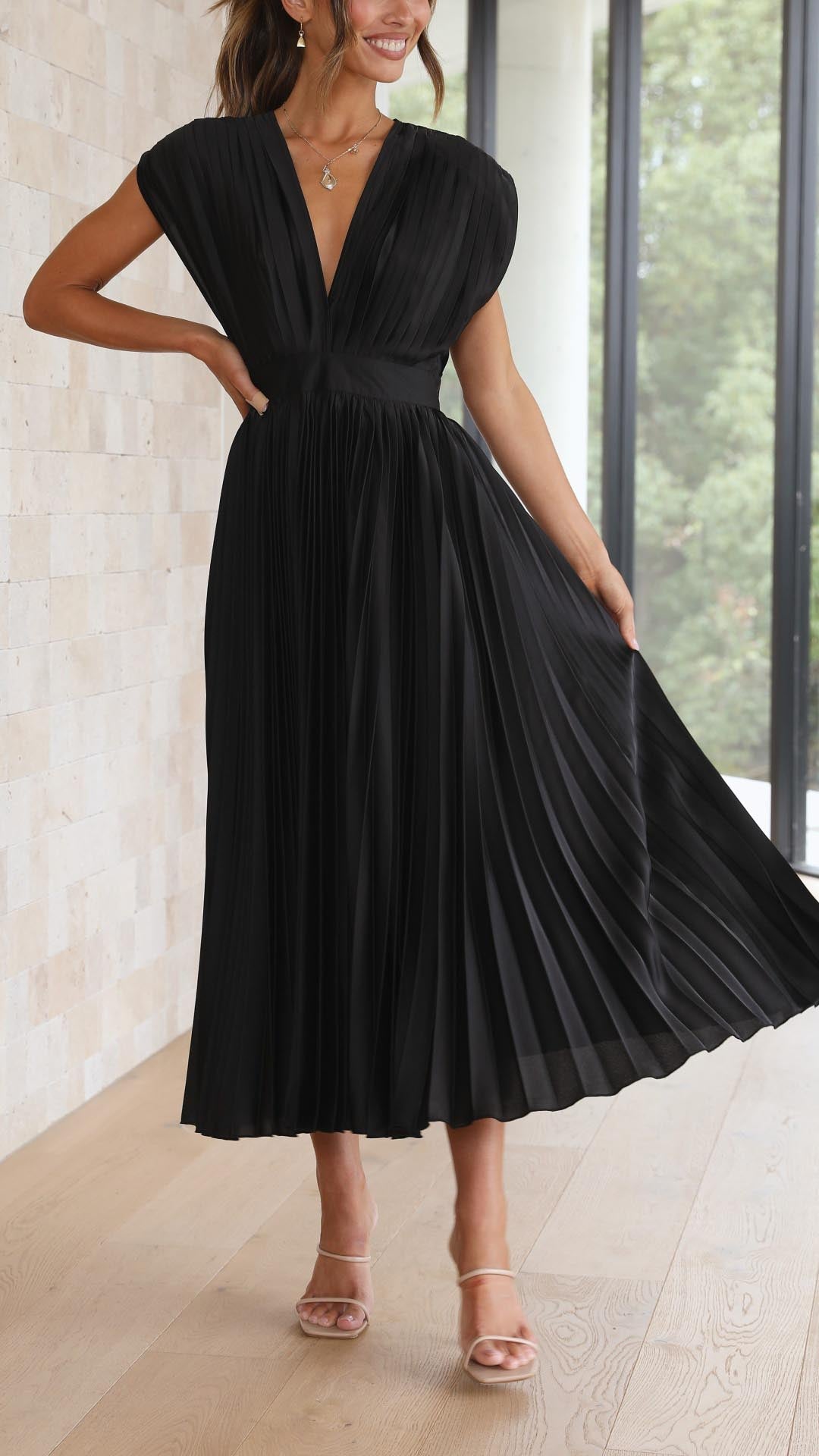 Woman wearing a black pleated dress in an indoor setting