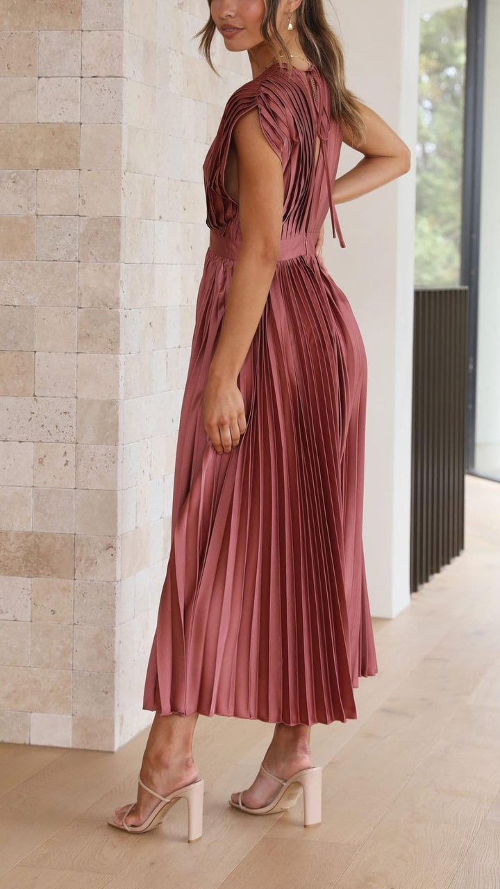 Woman wearing a pleated dress in a neutral indoor setting