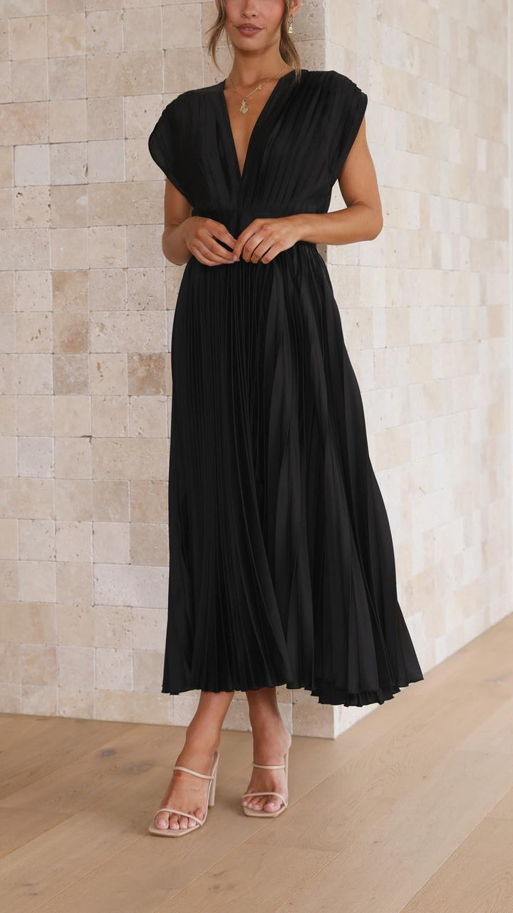 Woman wearing a black dress against a light stone wall.